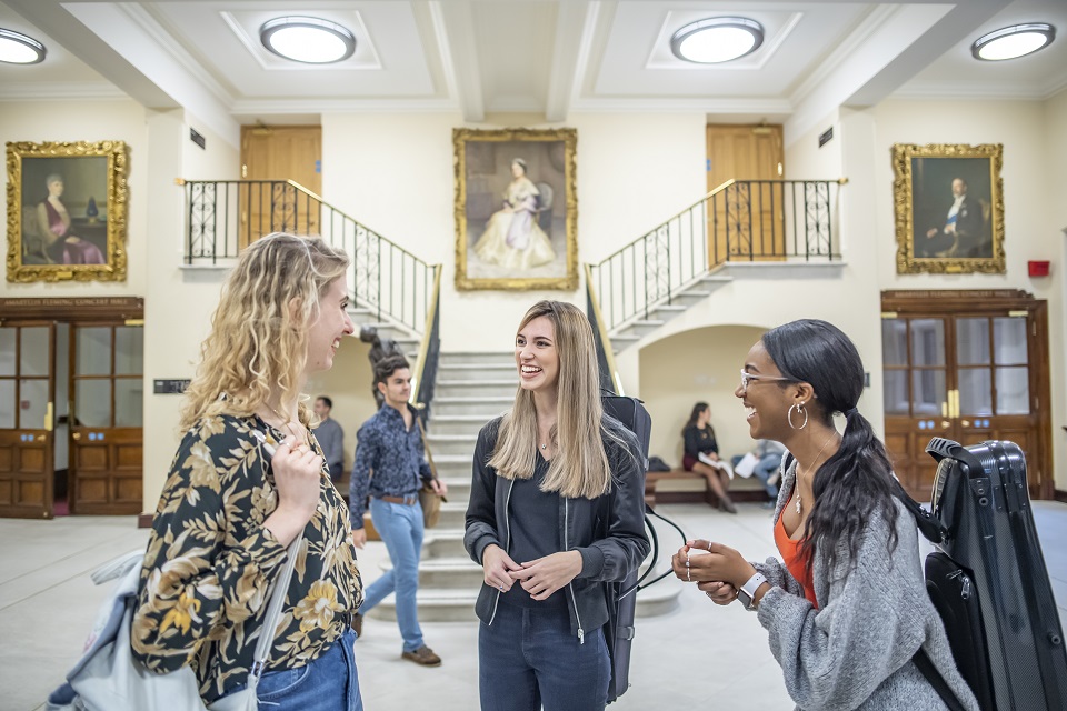 Three students stood talking in the RCM reception